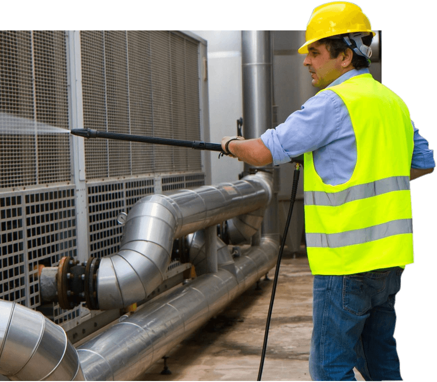 A man in yellow vest and hard hat washing pipes.