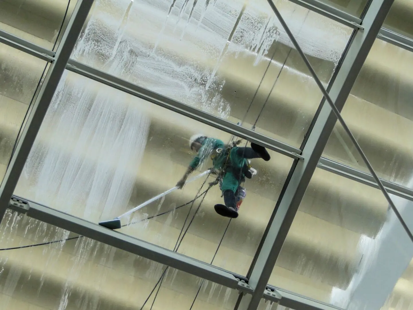 A person cleaning windows with a mop and a wet rag.