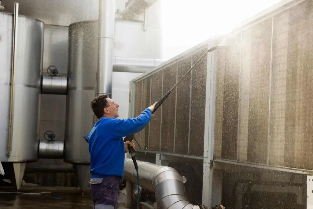 A man is cleaning the air conditioning unit.